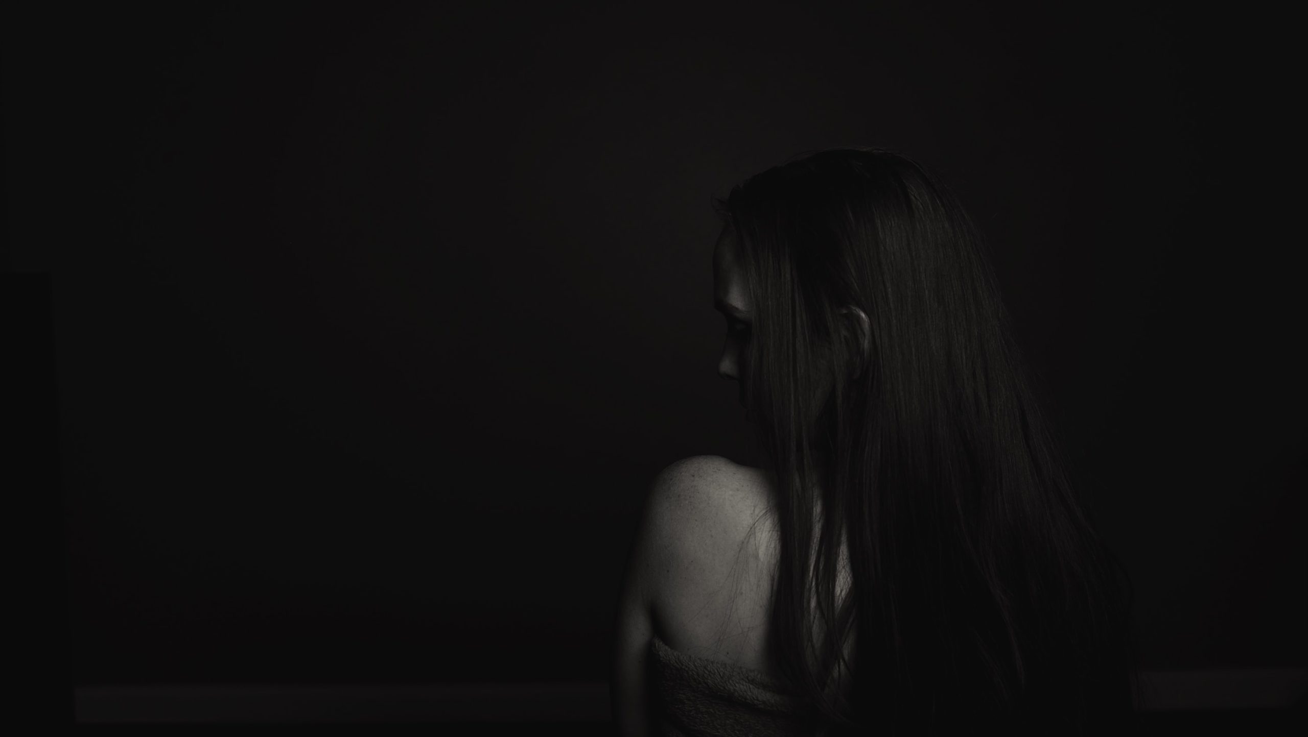 a woman looks over her shoulder in a dark space