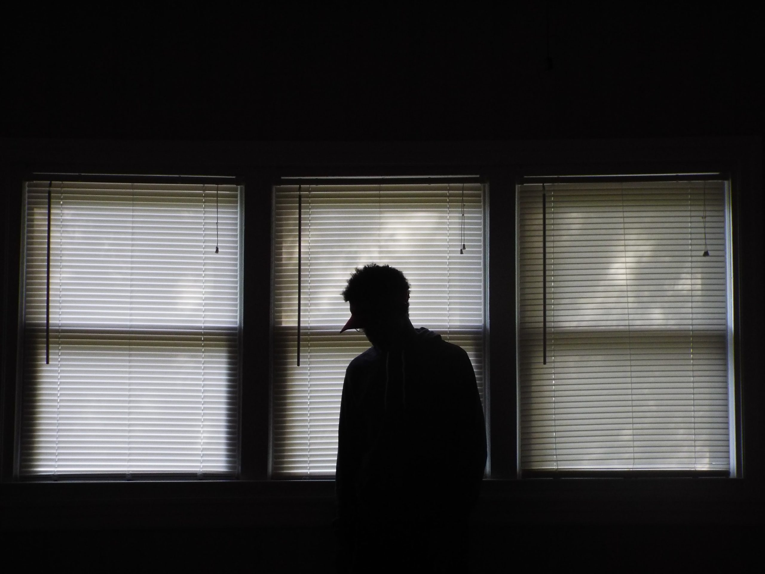 a person standing in front of windows with the blinds closed