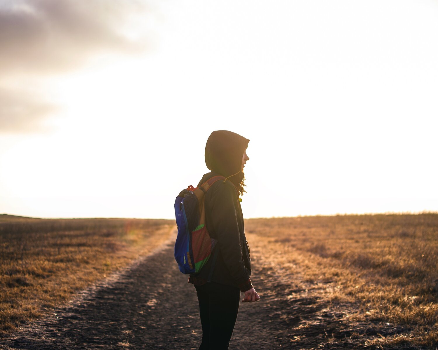 Woman wearing backpack staring into the distance.