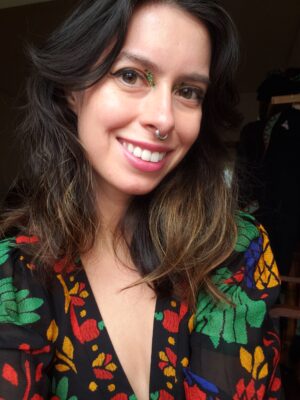 Amanda Boman, a story contributor, wearing a silver septum piercing and a black top with colorful floral embroidery.