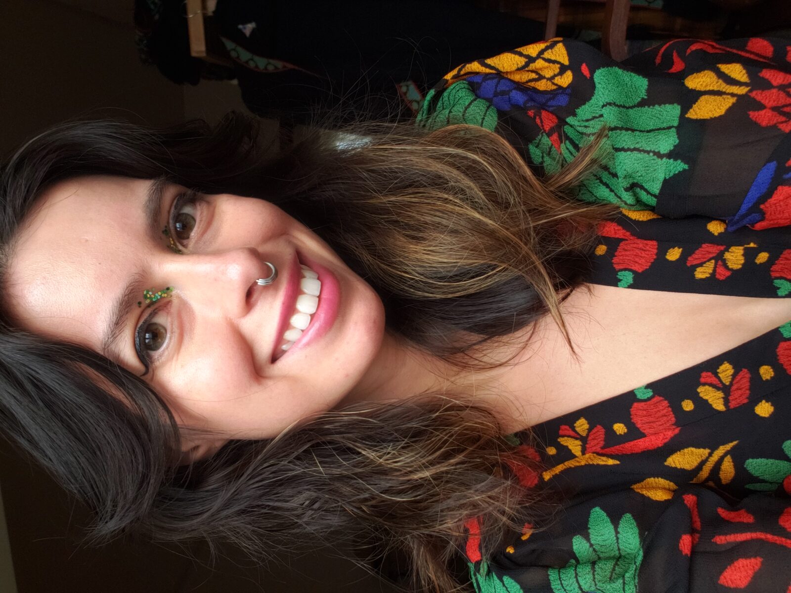 Amanda Boman, a story contributor, wearing a silver septum piercing and a black top with colorful floral embroidery.