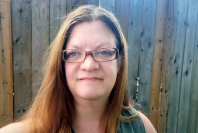 Anita Jackson, story contributor, standing in front of a wooden fence.
