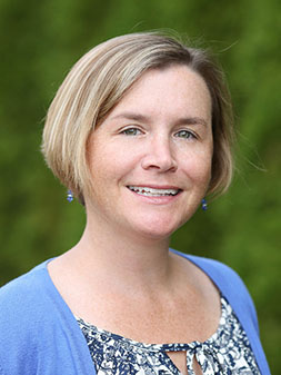 Diana LaChance, outside, smiling, with a floral top and blue sweater.