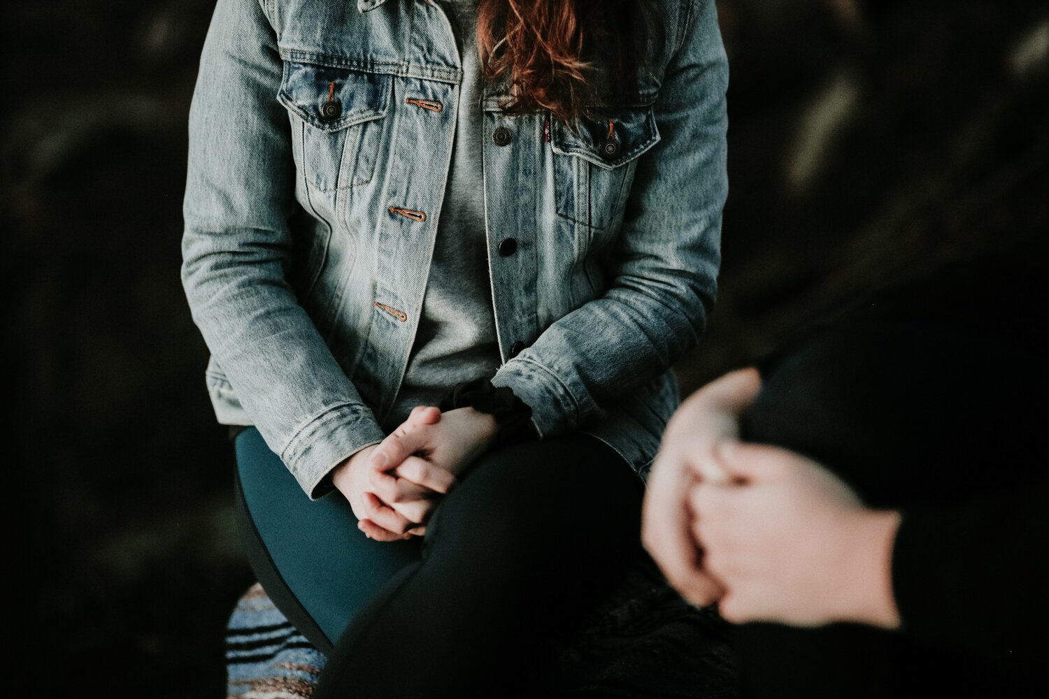 Cropped photo of two people sitting together with their hands in their laps.