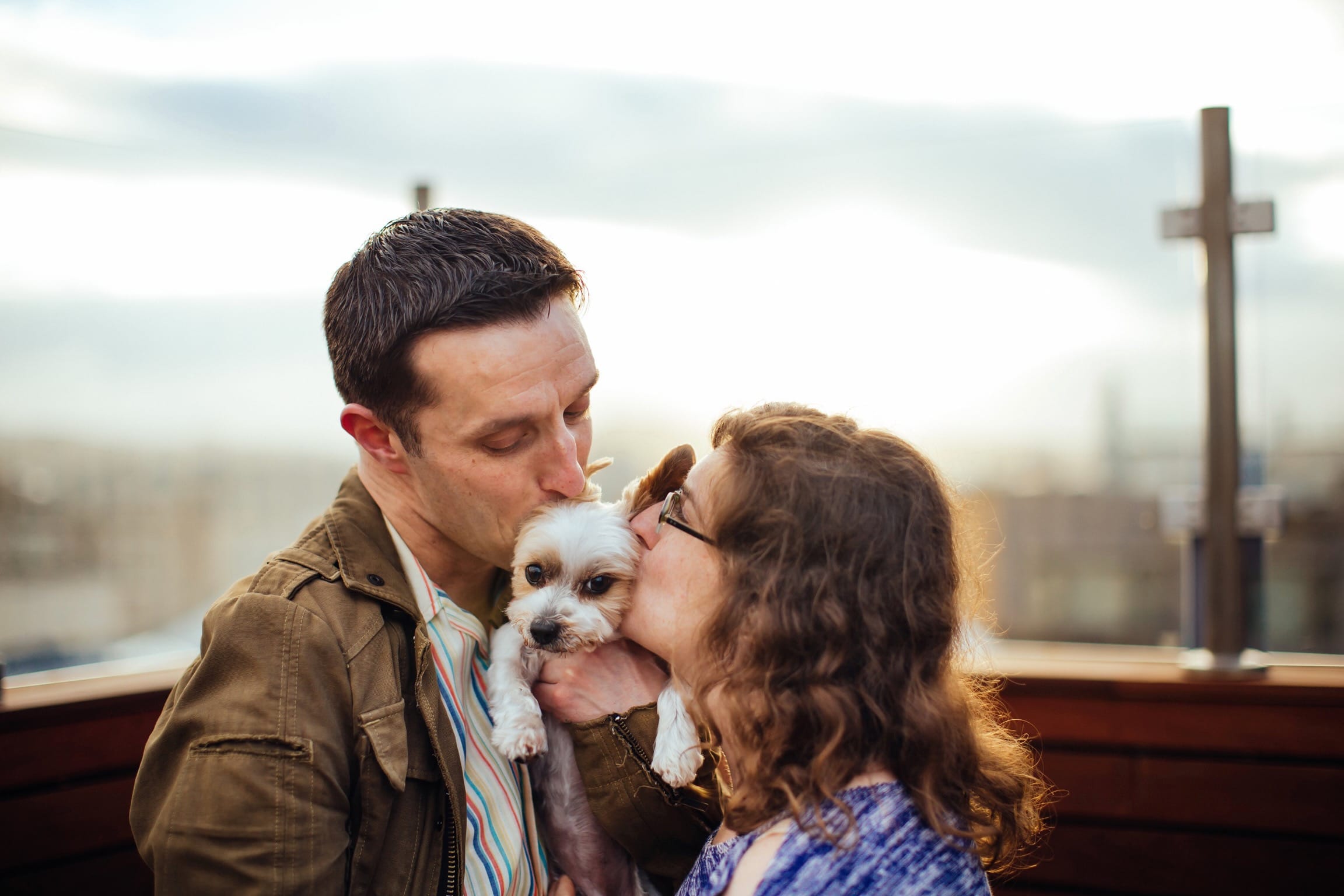 Becca and Chris kissing a puppy.