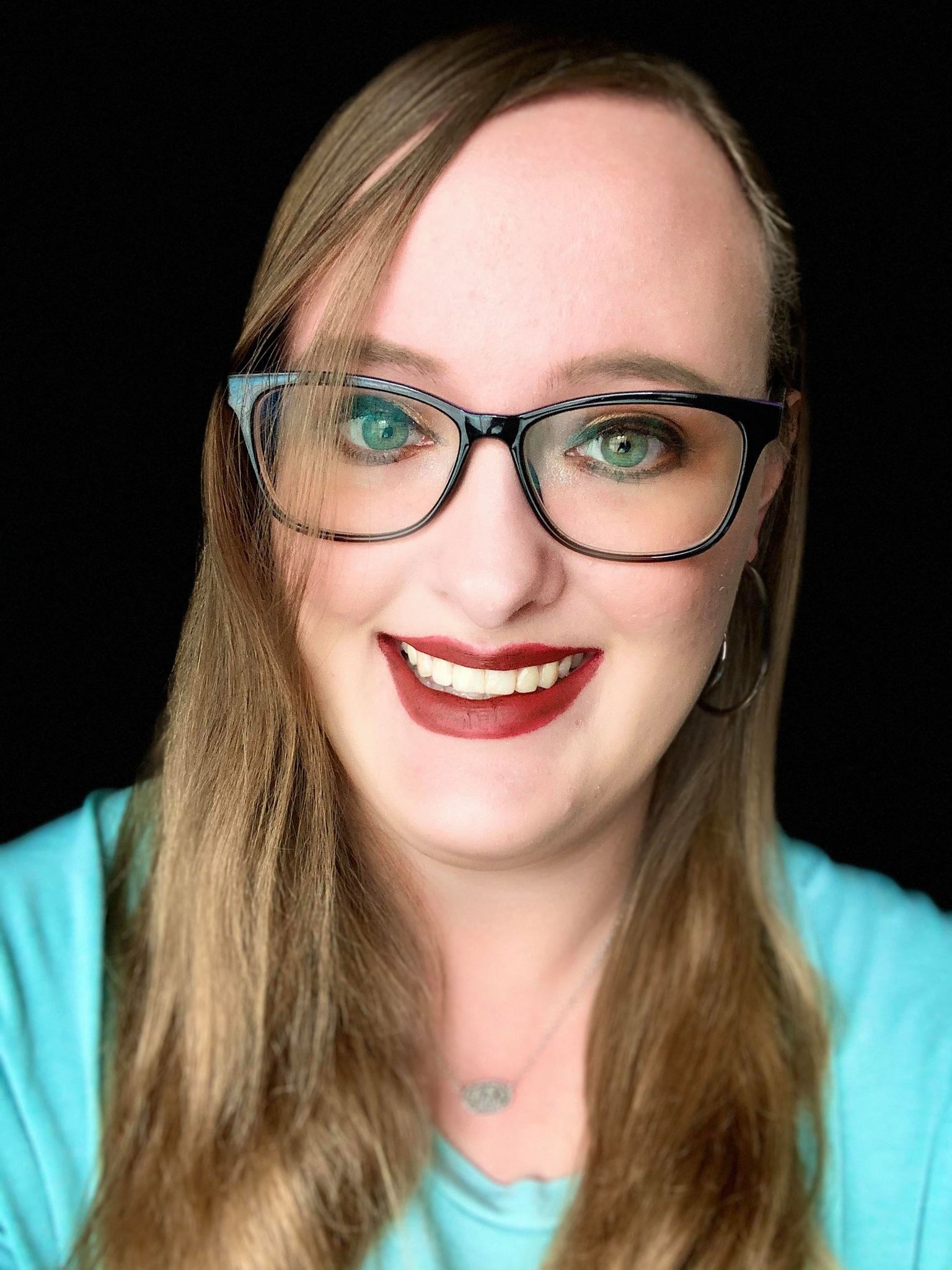 Hollyn Donovan, story contributor, wearing black frames and a bright teal top.
