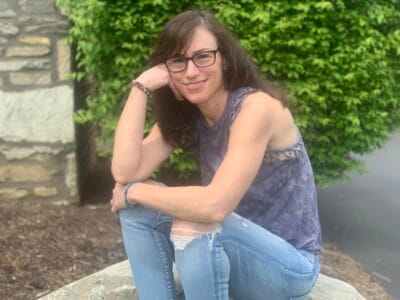 Ronni Robinson, story contributor, wearing a tank top and jeans and sitting outside.
