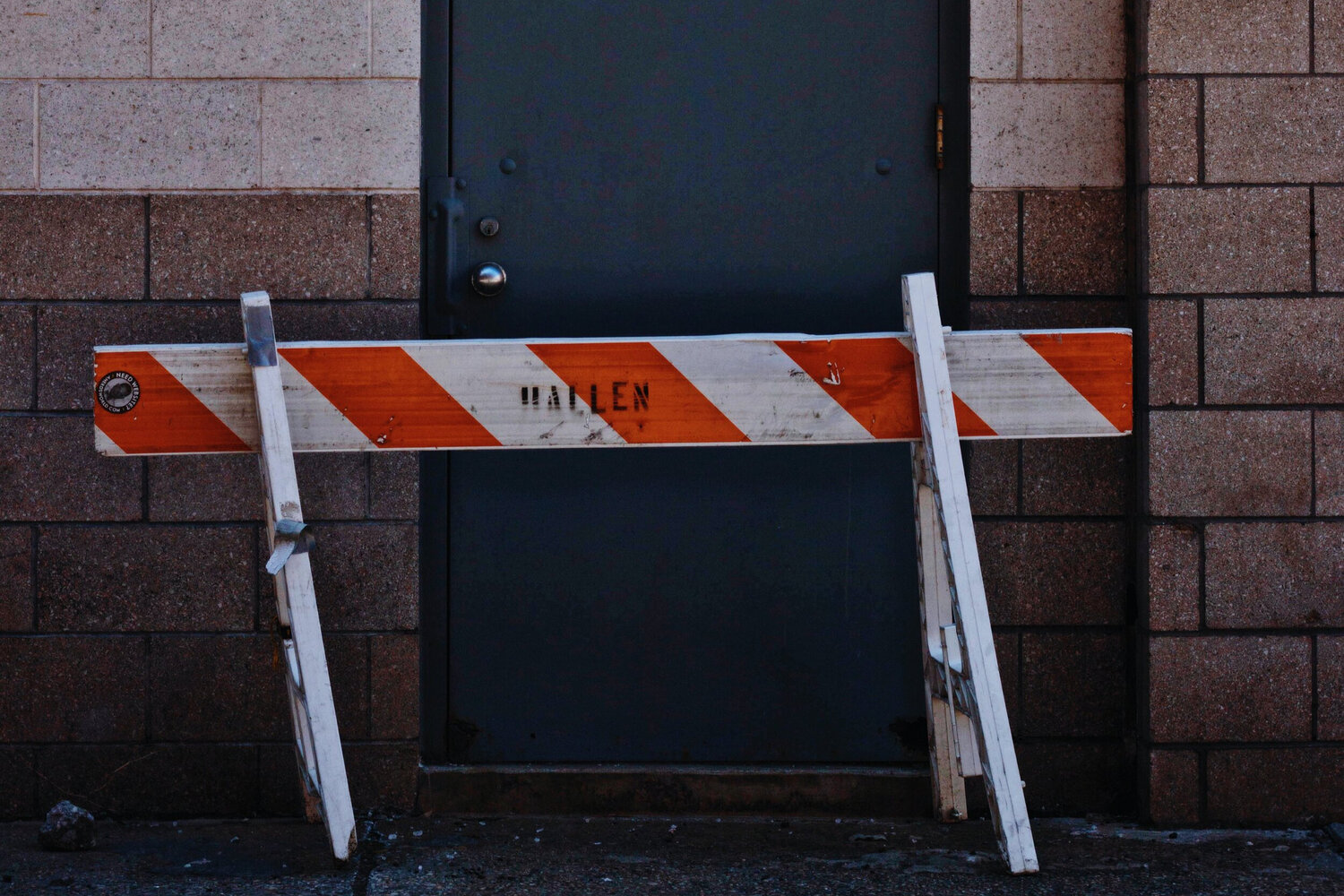 Orange and white striped barrier in front of a door.