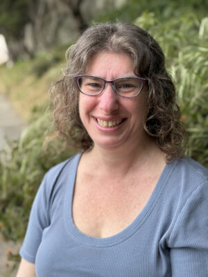 Rebecca Massie, Executive Director of Better Because Collective. She's smiling, has curly hair, and wears glasses.