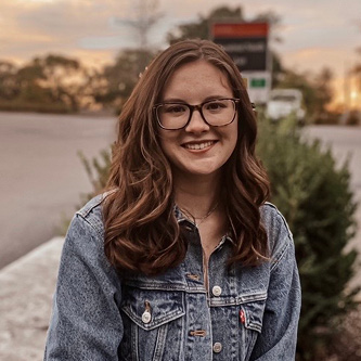 Sidney Jarboe sitting, wearing a jean jacket, smiling.