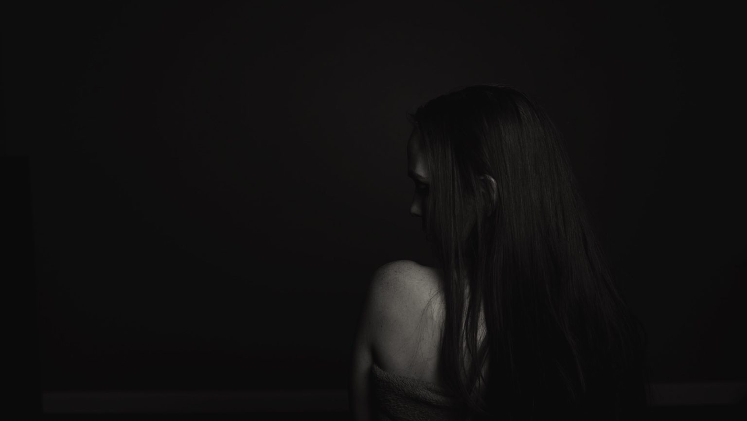 Woman looking over her shoulder in a dark space.