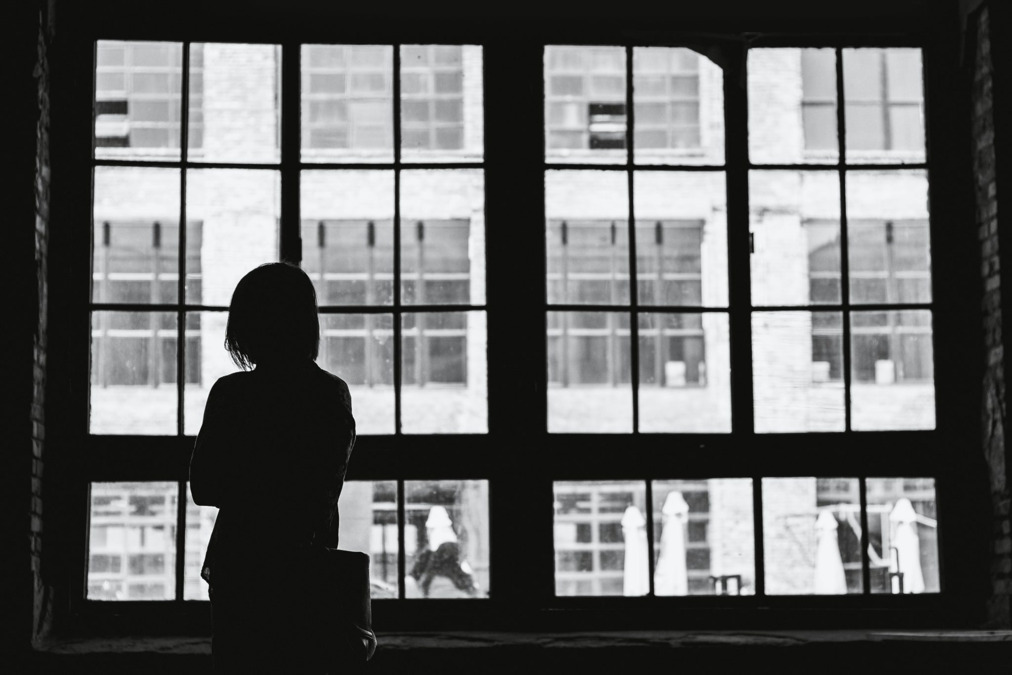 Black and white photo of a woman looking out the window.