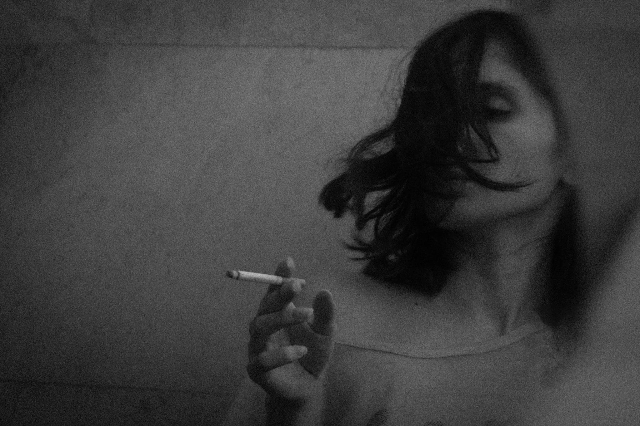Black and white photo of a woman holding a cigarette.