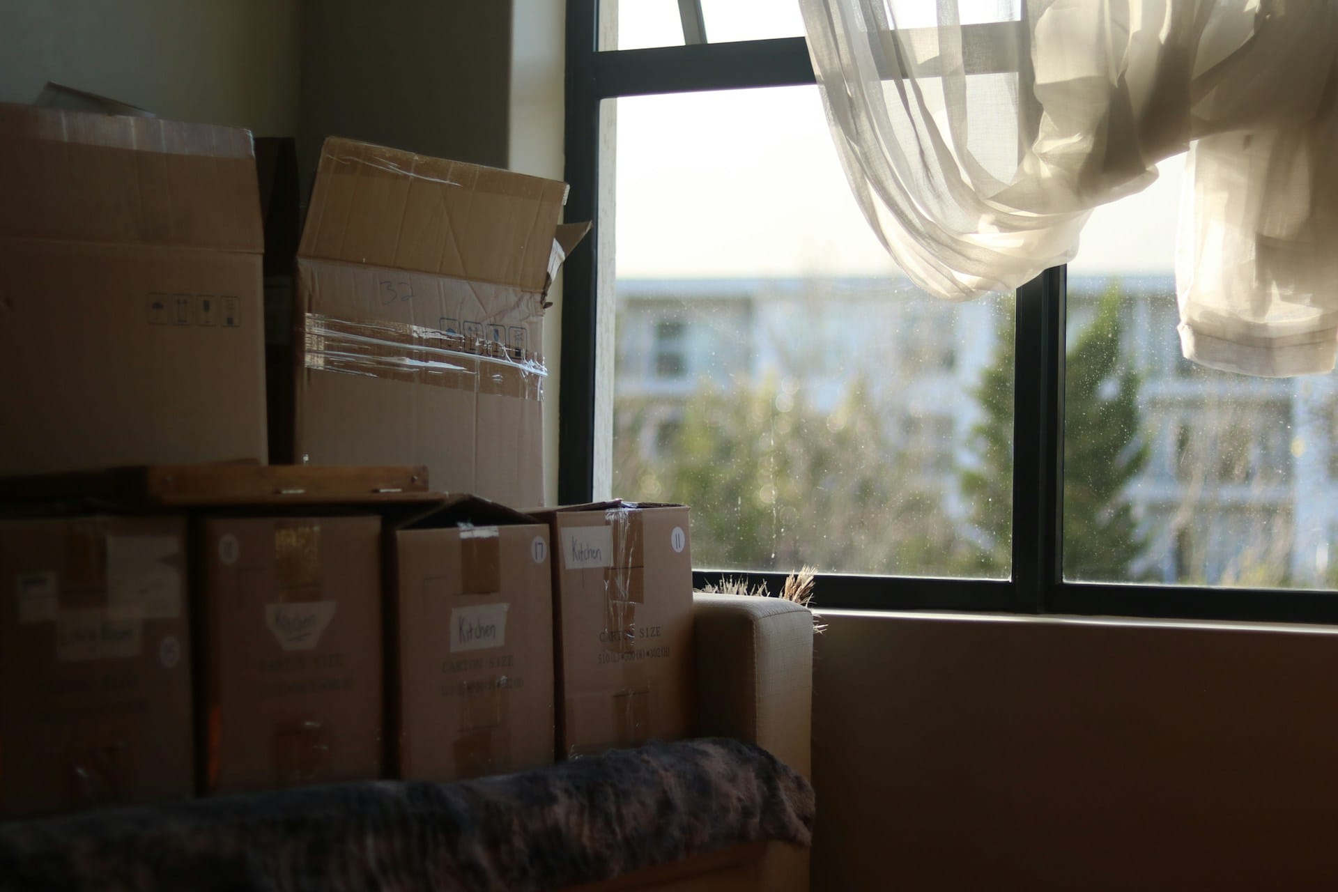A room with packed moving boxes and a window.