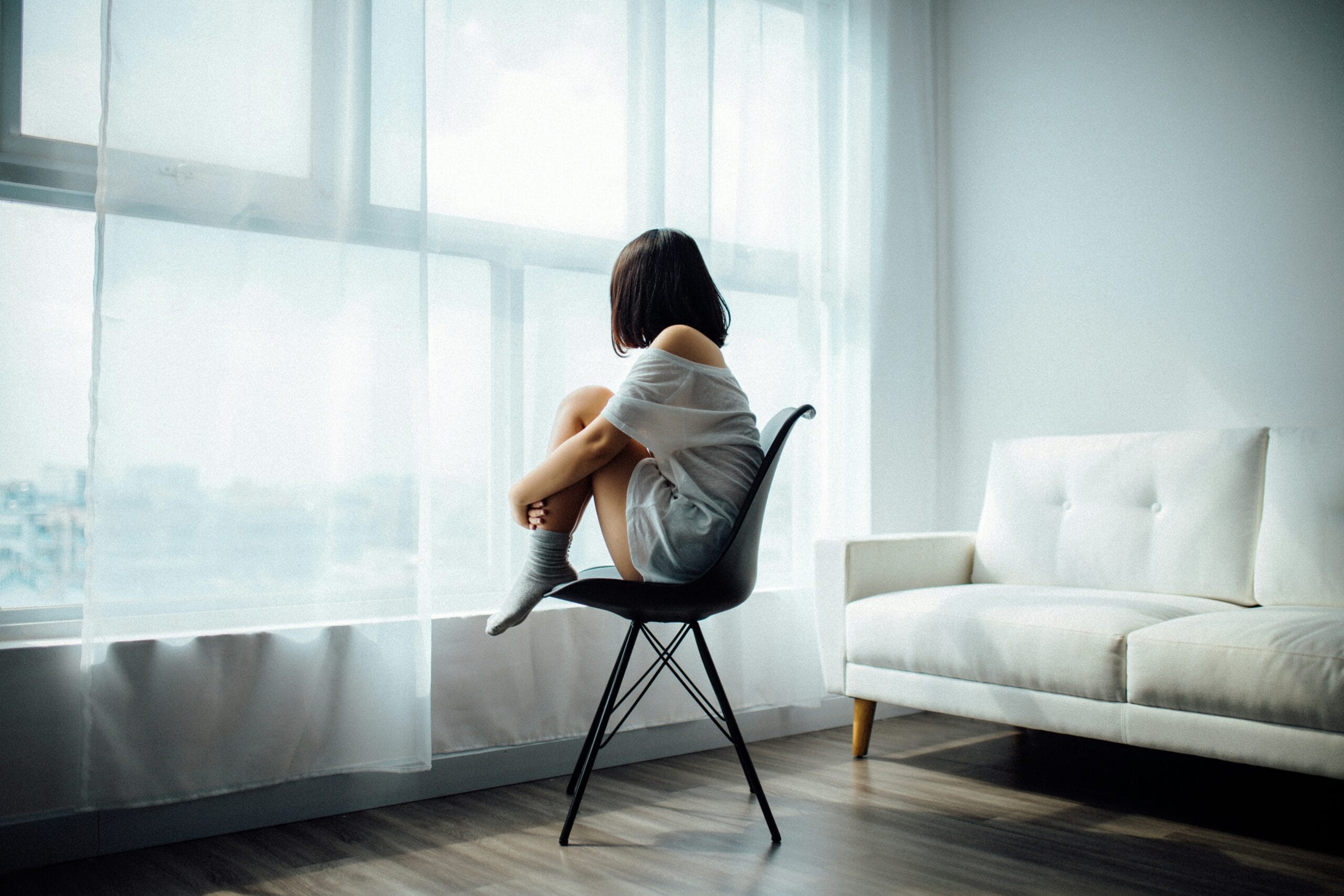 Woman sitting on black chair in front of glass window. 