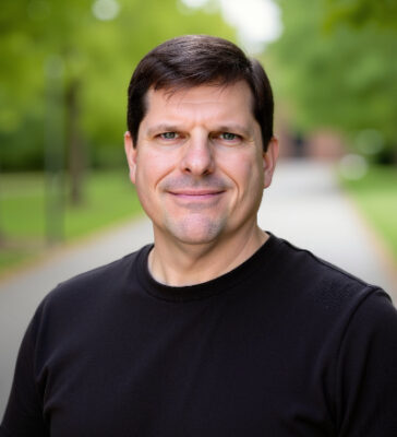 Charles Metzger outside, smiling, wearing a dark shirt.