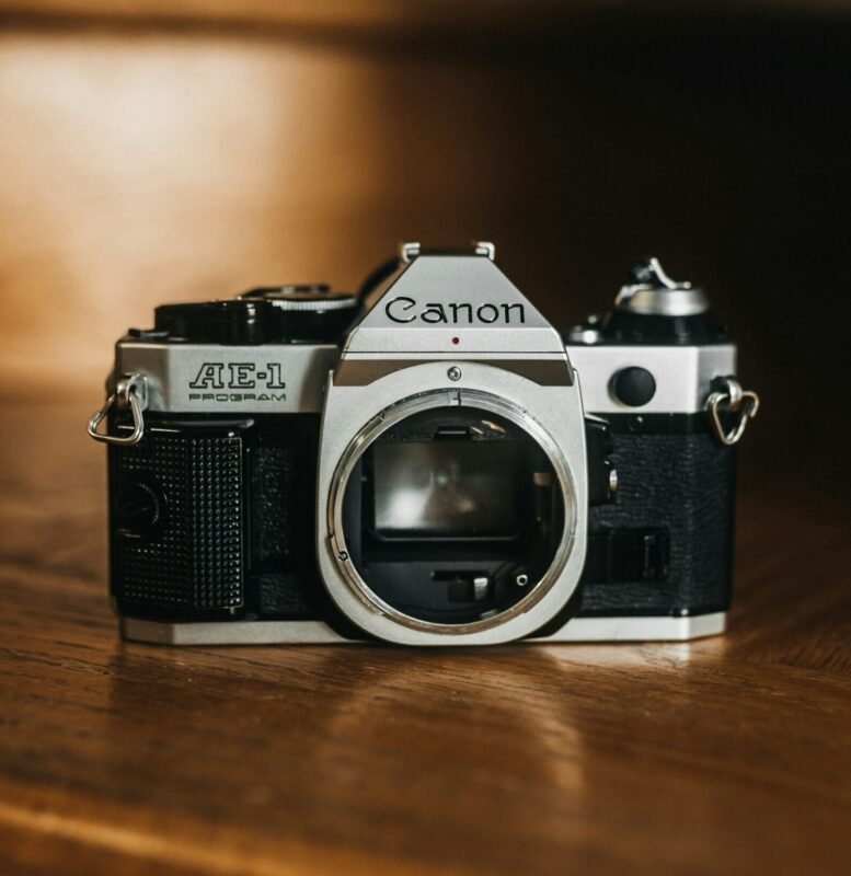 Anonymous contributor image, featuring a camera sitting on top of a wooden table.