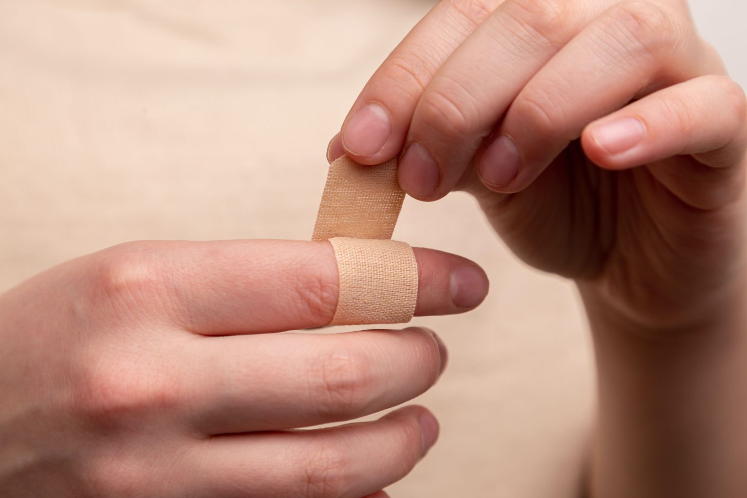 A person wrapping a bandaid around their index finger.