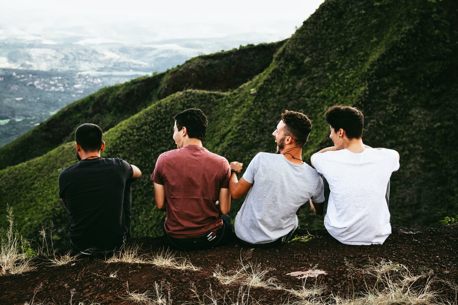 Four friends sitting on a lookout point of a mountain.