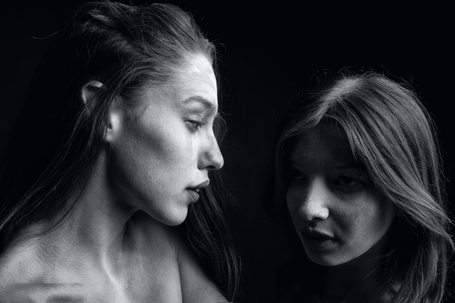 Black and white photo of two women looking at each other.