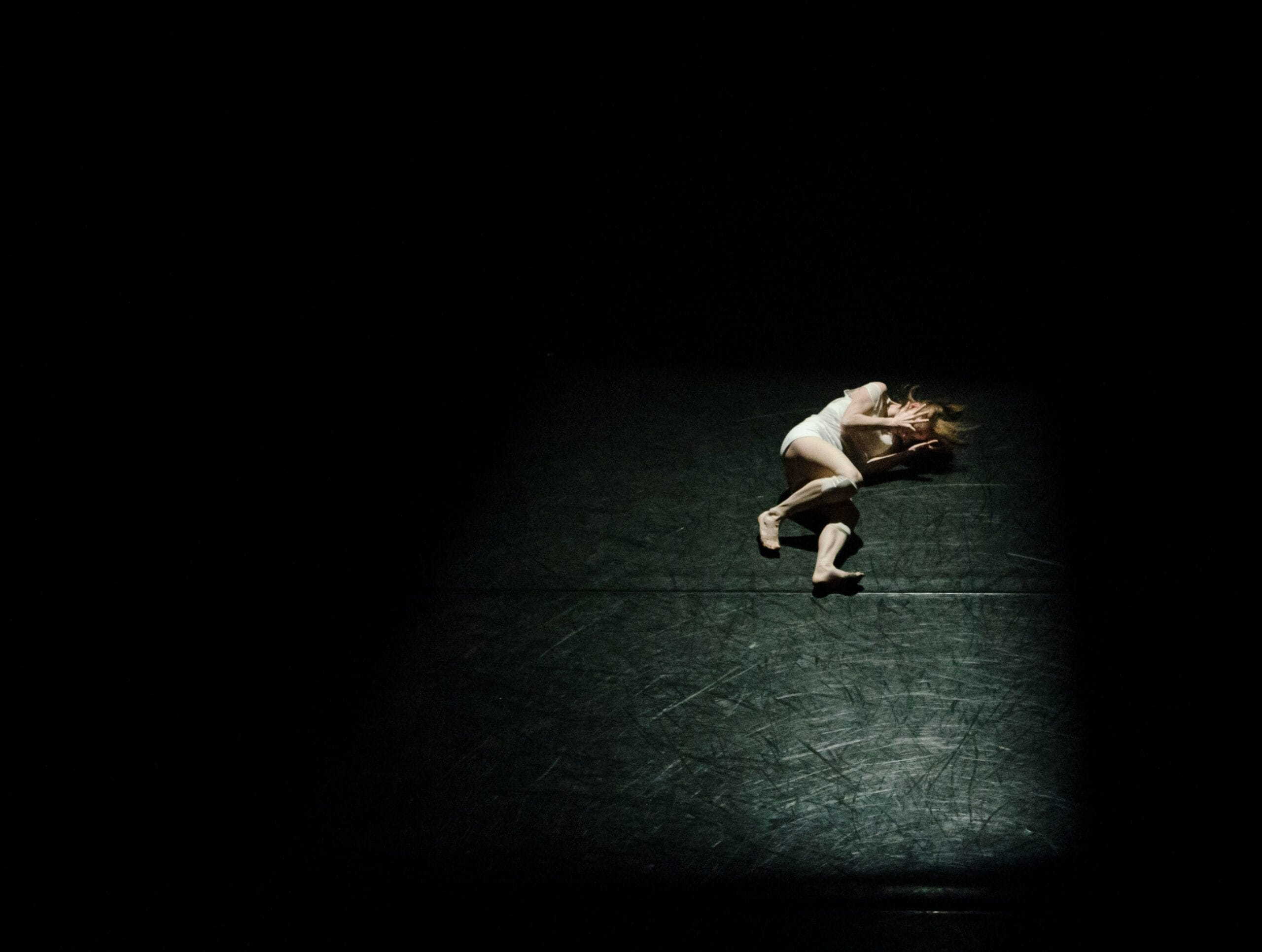 A person laying on the ground in the dark.