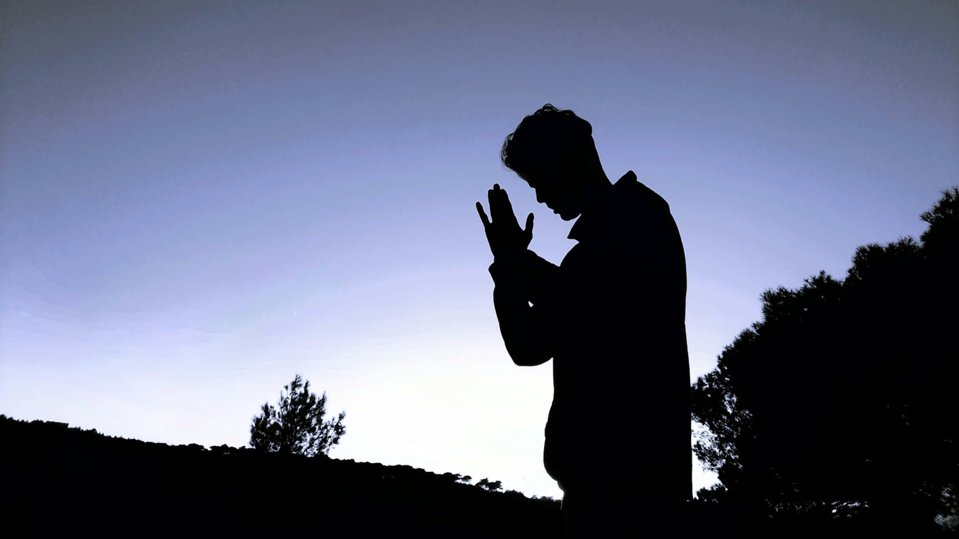 A silhouette of a man praying.