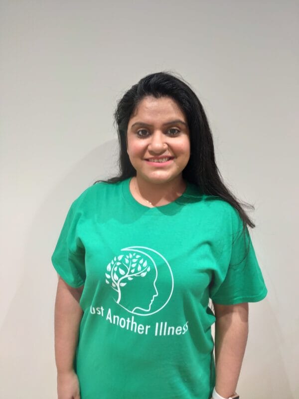 Ridhima Bhasin, story contributor, wearing a bright green shirt with text that reads "Just Another Illness", a mental health awareness campaign of hers.