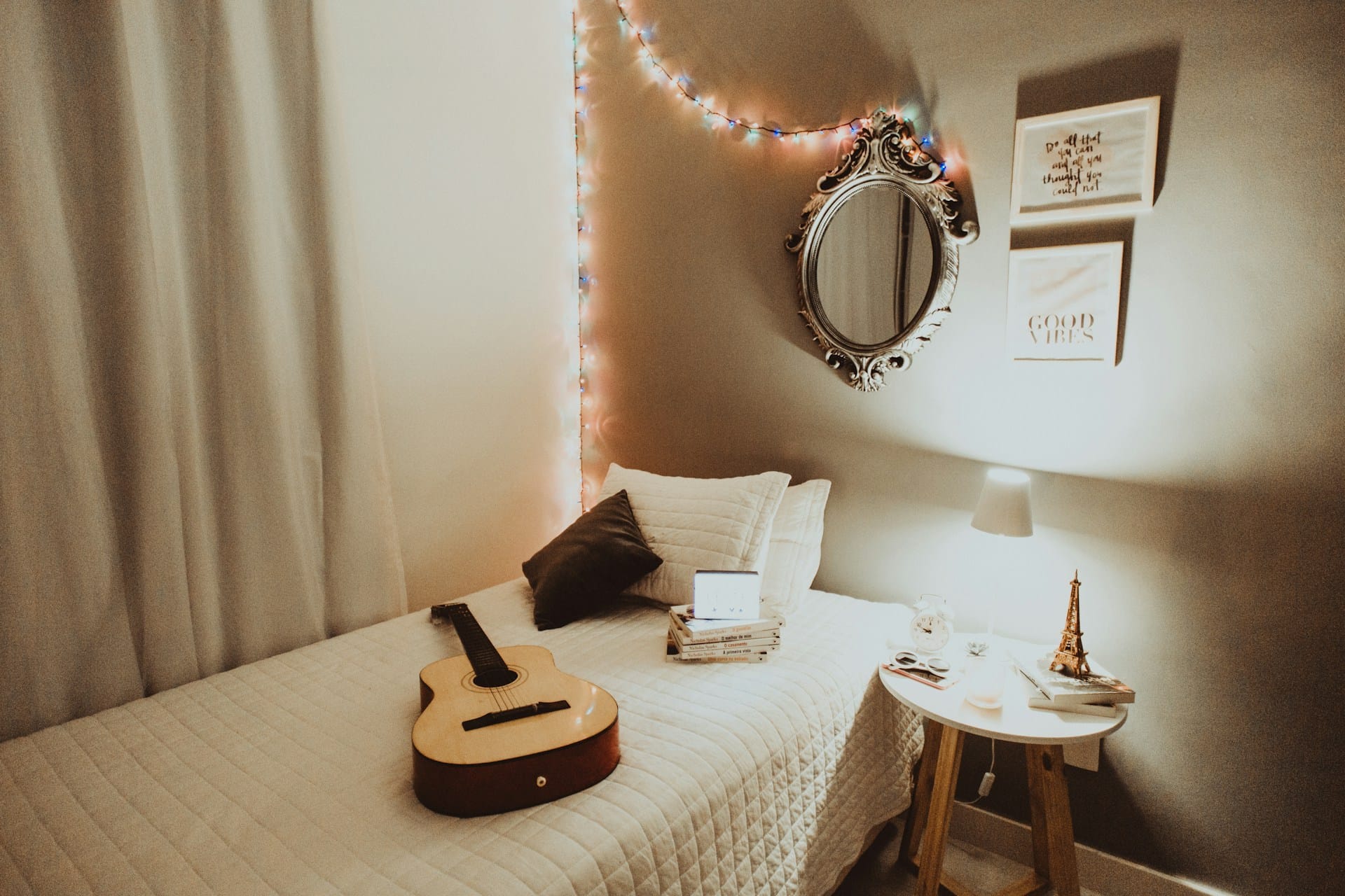 Guitar on top of a bed in a simple bedroom.