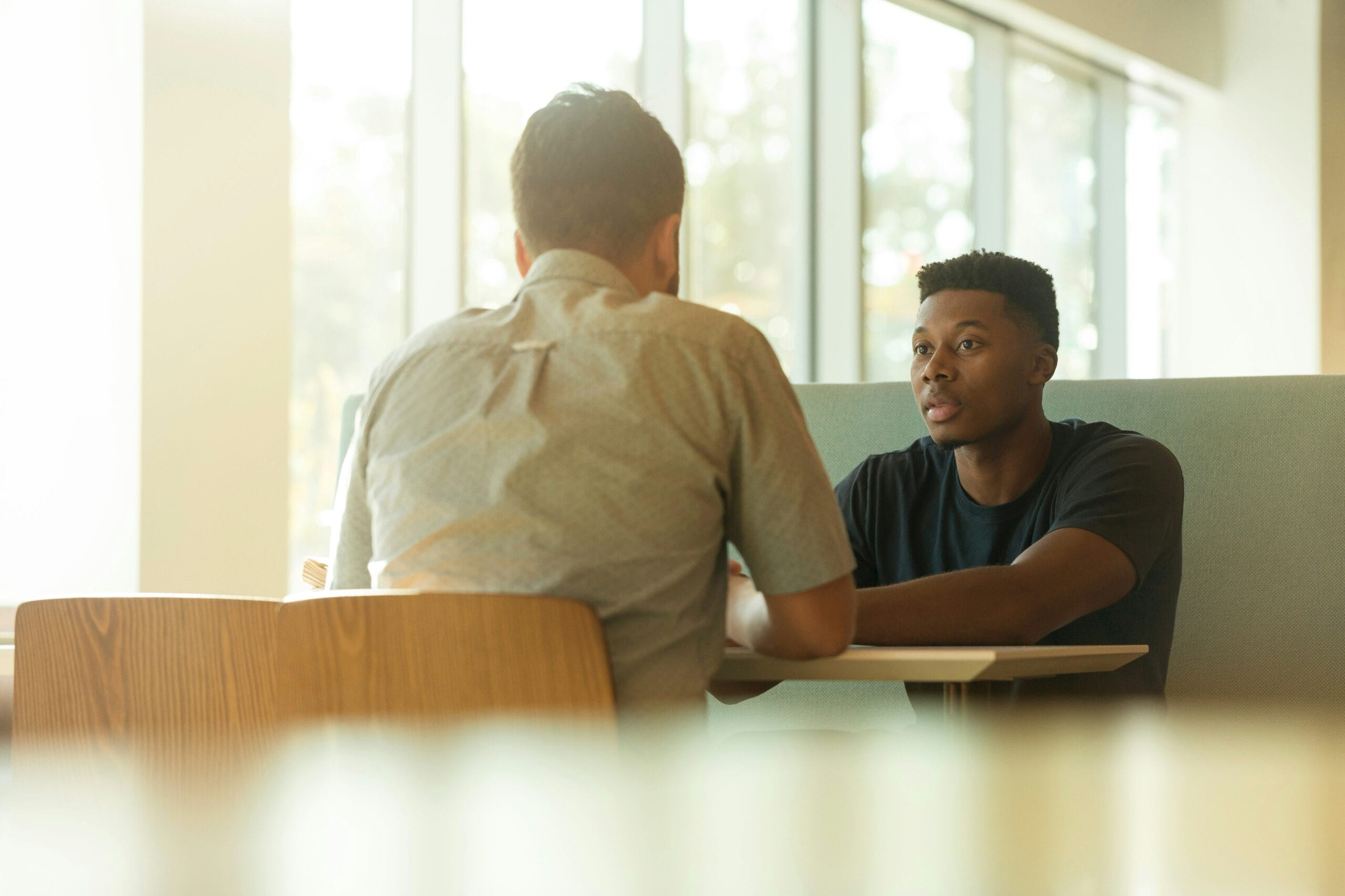 Two men talking in a cafe booth.