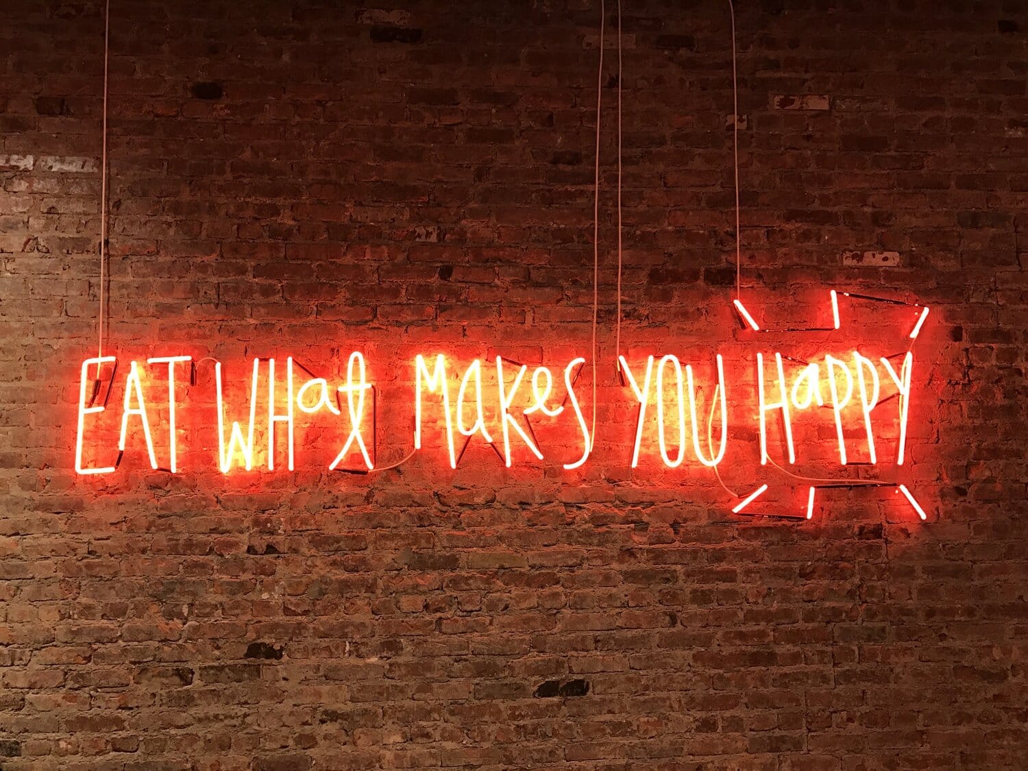 Neon sign of the words "Eat What Makes You Happy"