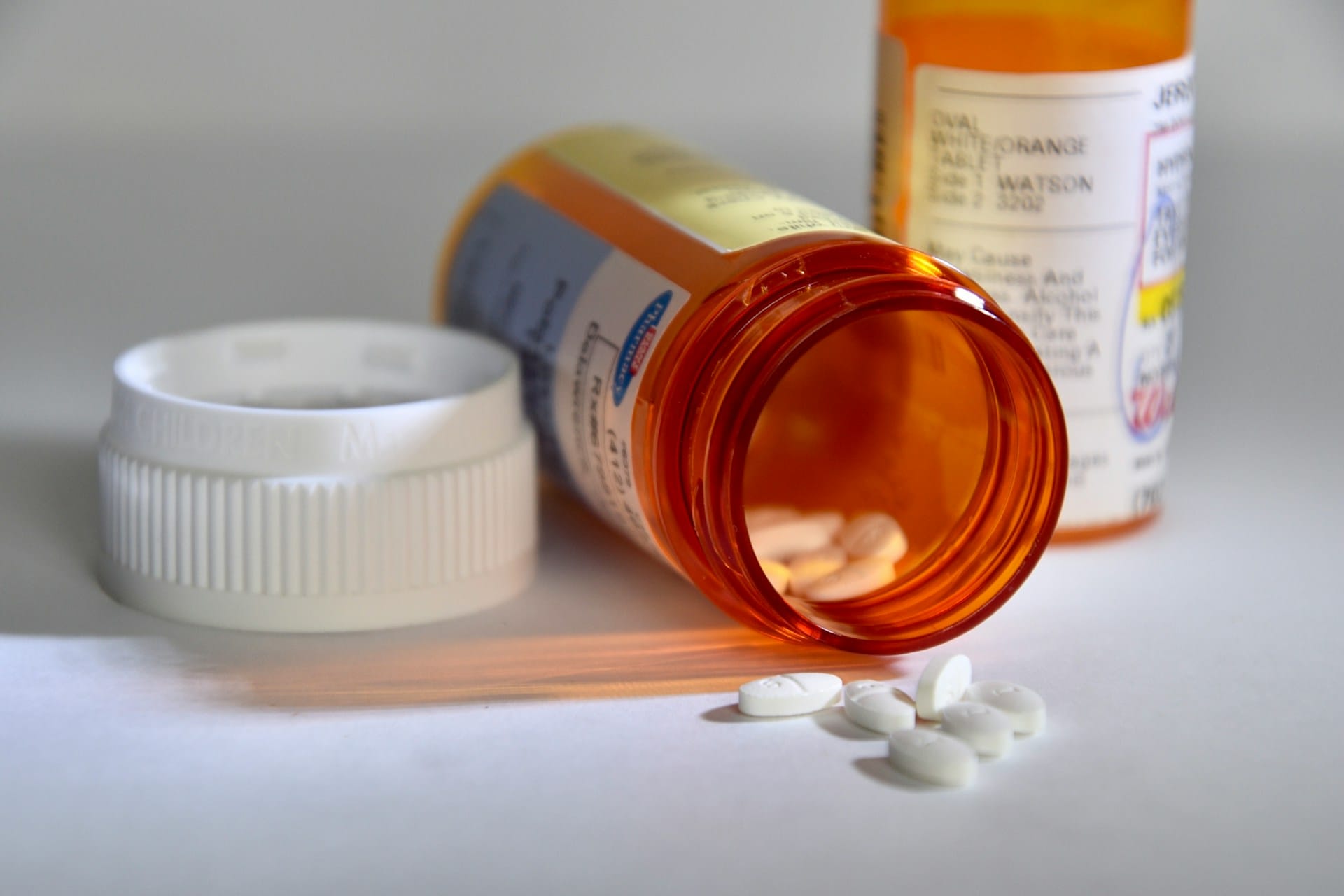 Orange and white prescription bottle with pills coming out.