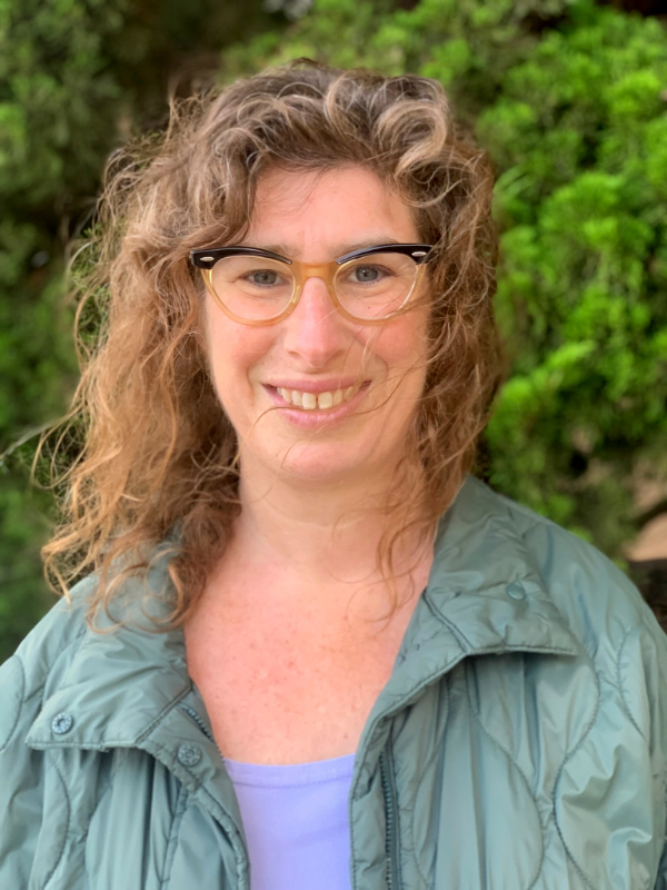 Rebecca Massie, Executive Director of Better Because Collective. She's smiling, has curly brown hair, and wears glasses.