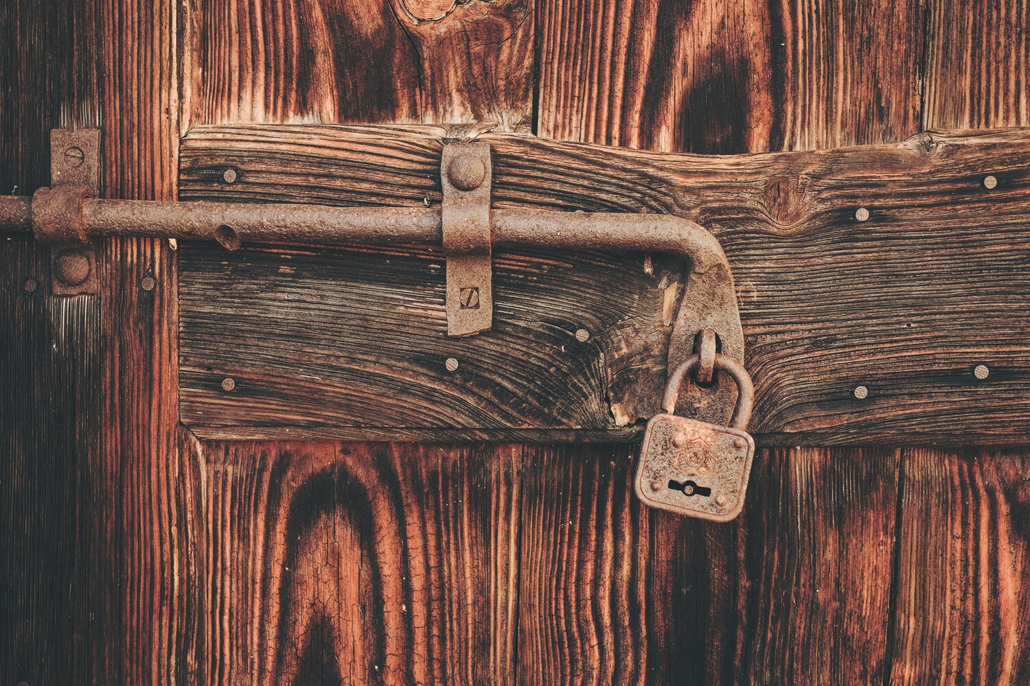 Rusted padlock on old wooden door.
