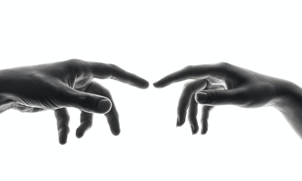 Two hands reaching towards each other, not touching.