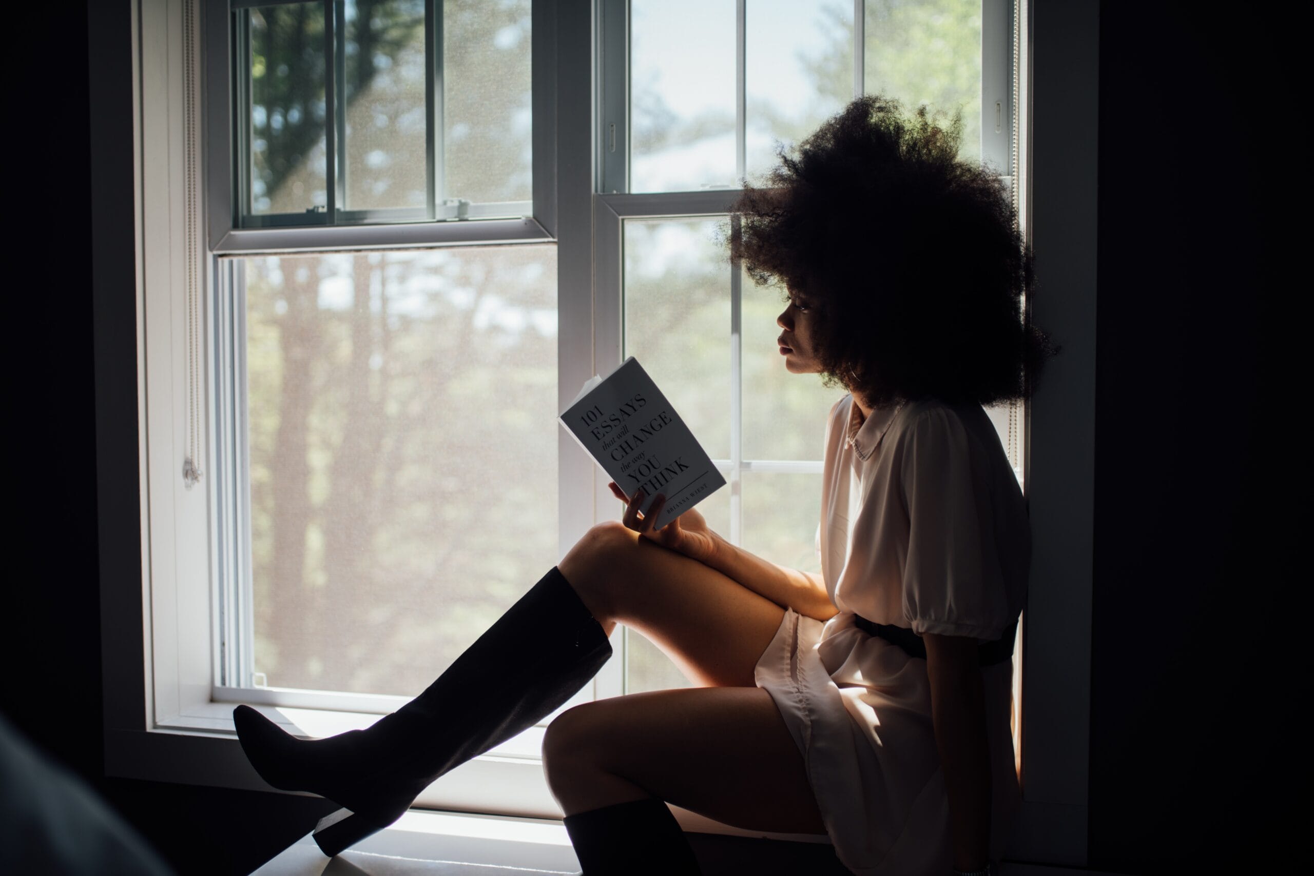 Girl sitting in a window reading a book.