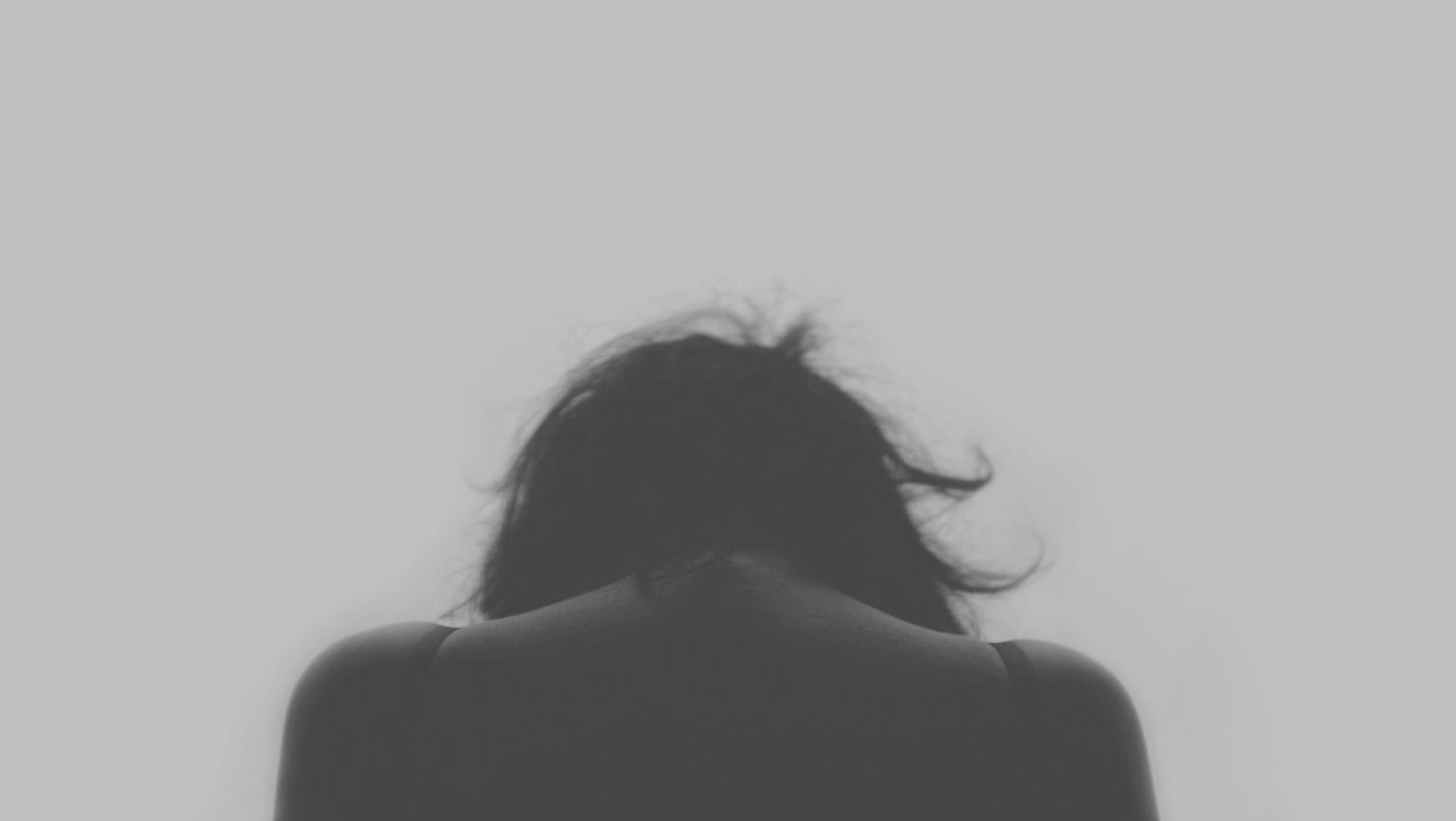 Black and white photo of a person looking down with their back facing you.