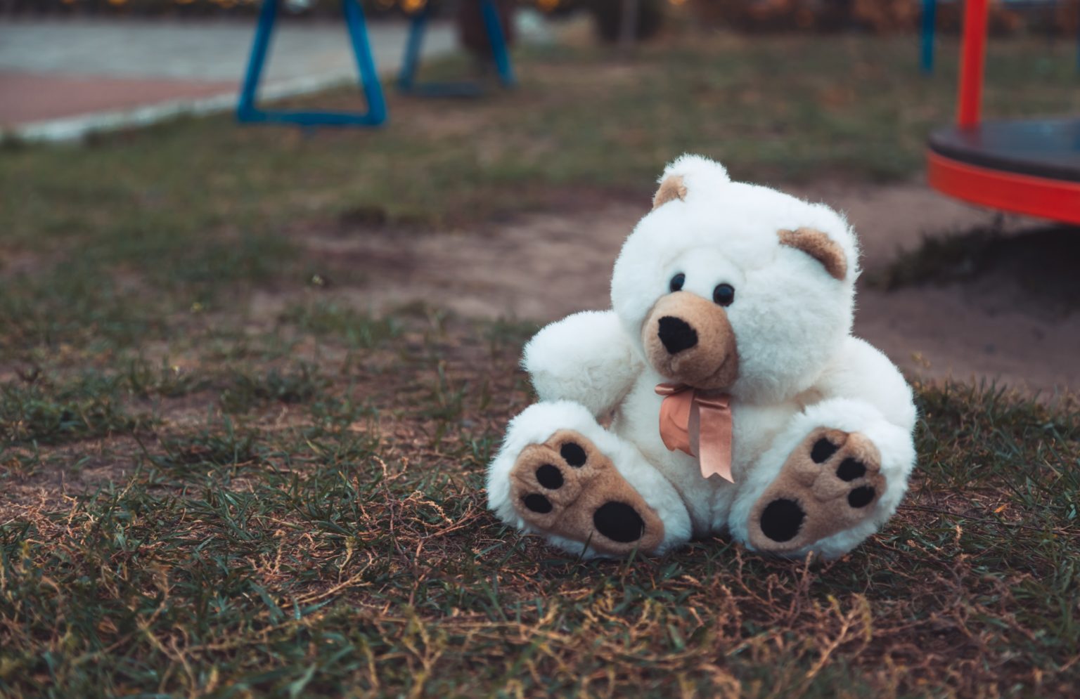 White teddy bear alone on a playground.
